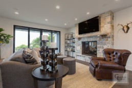 The living room with stone hearth in a Gordon James luxury lakeside mansion in Wayzata, Minnesota