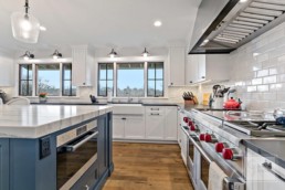 Picturesque country styled kitchen of a Gordon James' luxury home features a restaurant-quality stove top range and offers a view of Shaver's Lake in Wayzata, Minnesota