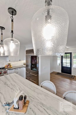 Artisan suspended lanterns illuminate sleek marble countertops of a Gordon James luxury home in Wayzata, Minnesota.